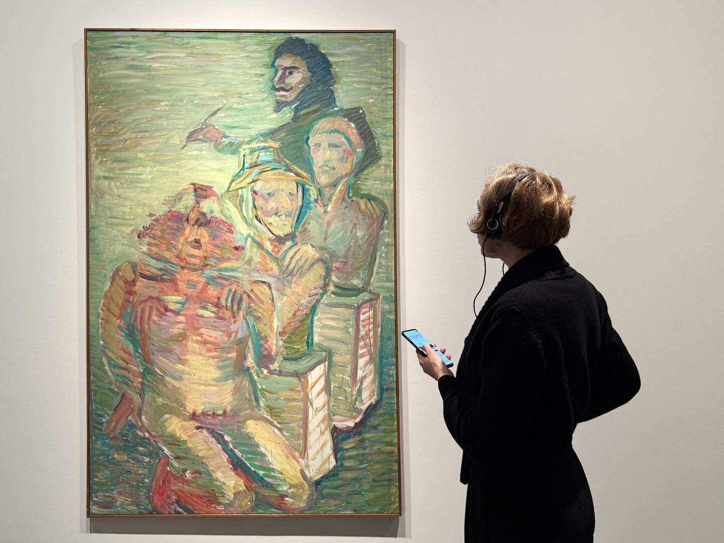 Eine Frau mit Kopfhörern vor dem Werk »Traditionskette« von Maria Lassnig