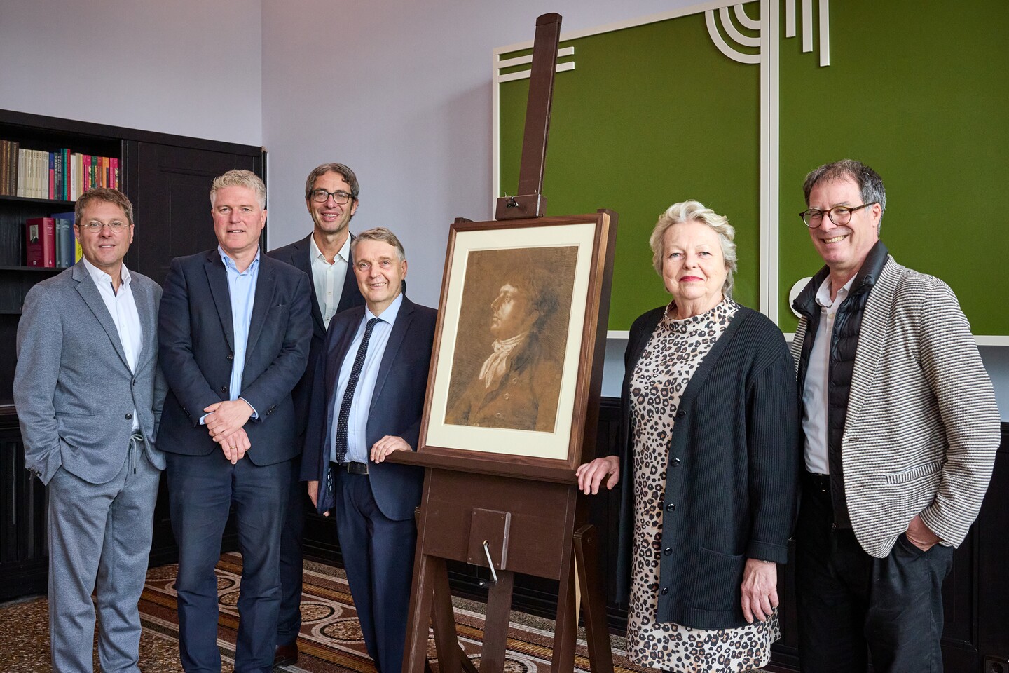 Fünf Personen stehen neben einem gerahmten Philipp Otto Runge Zeichnung auf einer Staffelei bei einer formellen Veranstaltung.