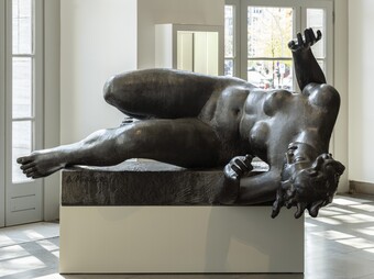 Große Bronzeskulptur von Aristide Maillol einer liegenden Frau auf weißem Sockel in hellem Museumsraum