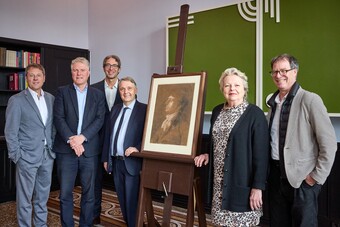 Fünf Personen stehen neben einem gerahmten Philipp Otto Runge Zeichnung auf einer Staffelei bei einer formellen Veranstaltung.