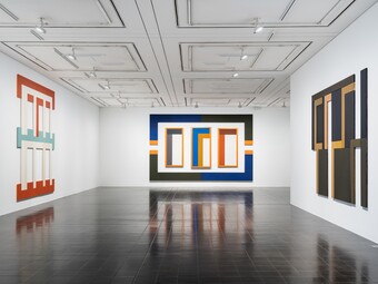 A modern art gallery featuring abstract paintings on white walls and a dark floor