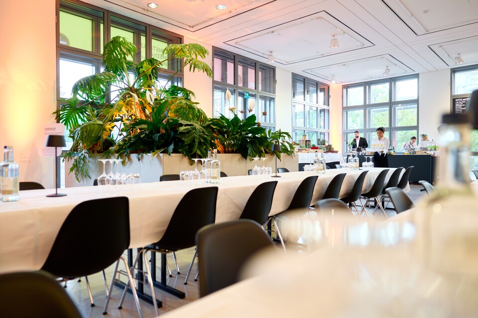 Das Foyer der Galerie der Gegenwart, langer Tafel, schwarzen Stühlen und Pflanzenarrangement