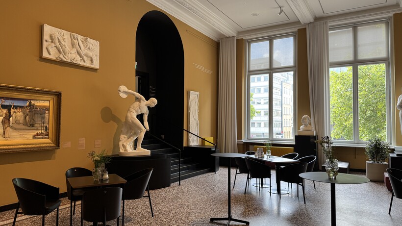 Eleganter Raum mit hohen Fenstern, Skulpturen und antiken Möbeln