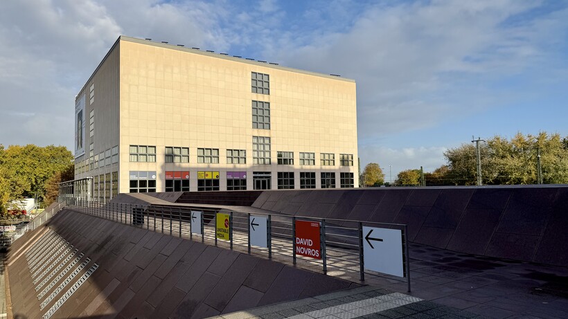 Modernes, weißes Gebäude mit großen Fenstern unter blauem Himmel